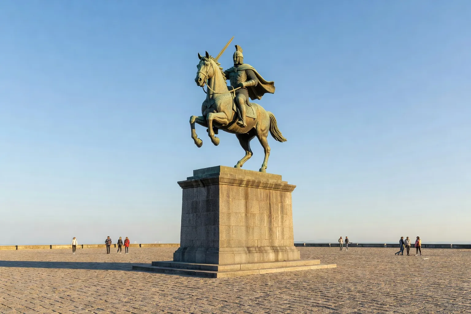 Monument équestre en bronze sur une vaste place pavée, évocation de la statue de Skanderbeg à Tirana